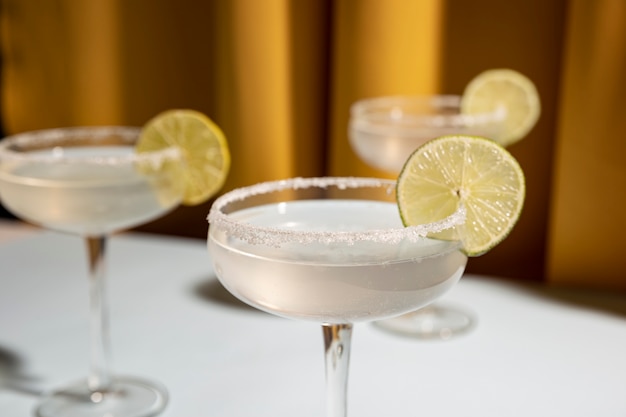 Three saucer glasses of margarita cocktail garnish with lime on table