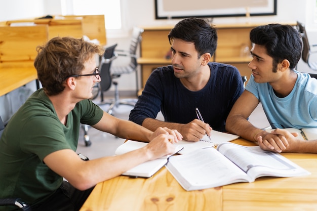 Three serious students doing homework and discussing task