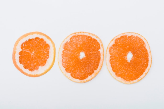 Free Photo three slices of orange arranged in row on white background