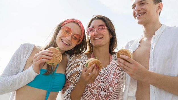 Three smiley friends outdoors eating burgers together