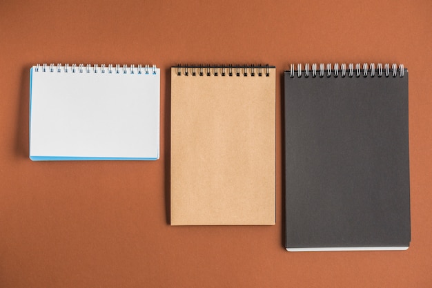 Three spiral notebooks on brown backdrop