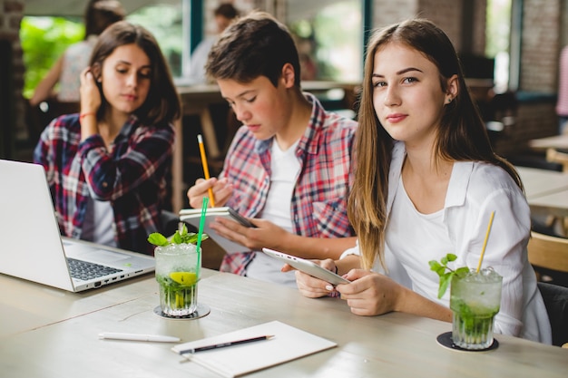 Three students with gadgets in cafe