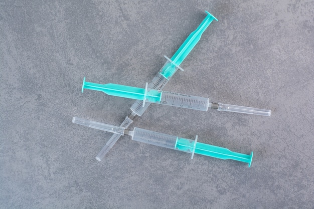 Three syringes with serum on marble surface.