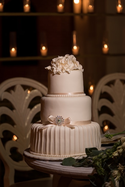 Three tiered white fondant wedding cake topped with buttercream flowers