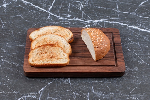 Three toasts arranged and bun on the board.