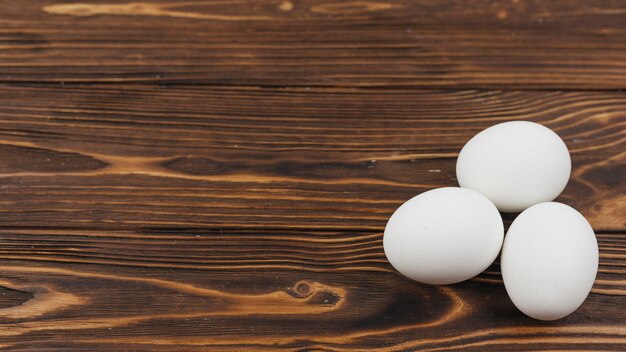 Three white eggs on wooden table