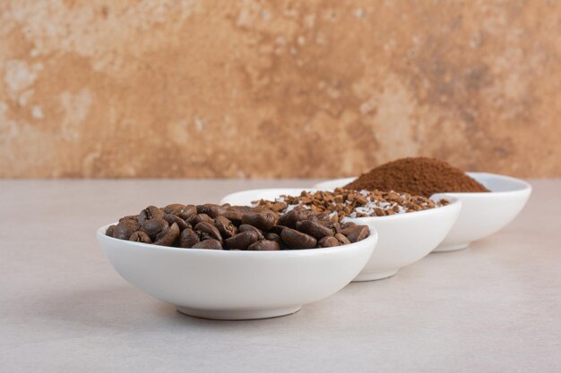 A three white plate full of coffee beans and cacao powder 