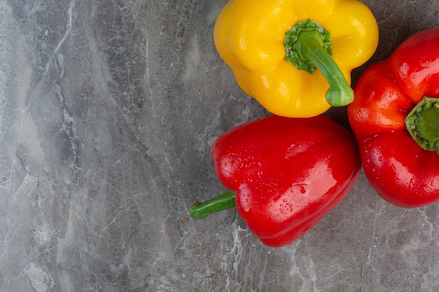 Free photo three whole peppers on marble background