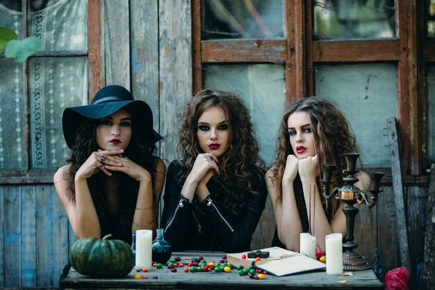 Three witches are sitting at a table on the eve of Halloween