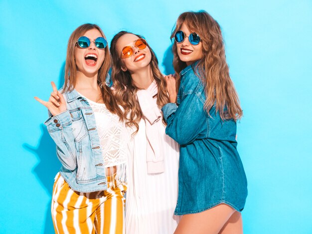 Three young beautiful smiling girls in trendy summer casual jeans clothes. Sexy carefree women posing. Positive models in sunglasses