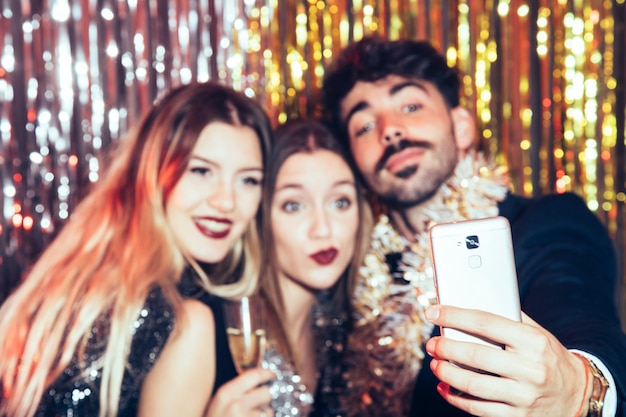 Free photo three young friends taking selfie on new years party