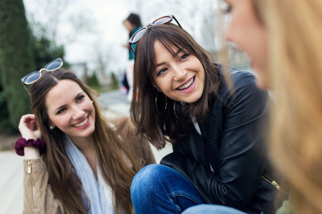 Three young women talking and laughing in the street.