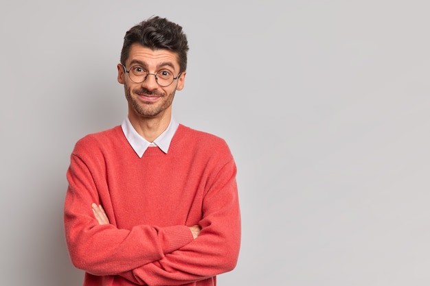 Timid satisfied European man crosses hands over chest