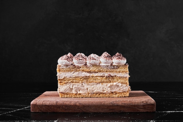 Tiramisu slice on a wooden platter .