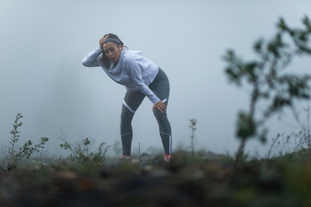 Free Photo tired athletic woman taking a break while being out of breath after the run during misty morning