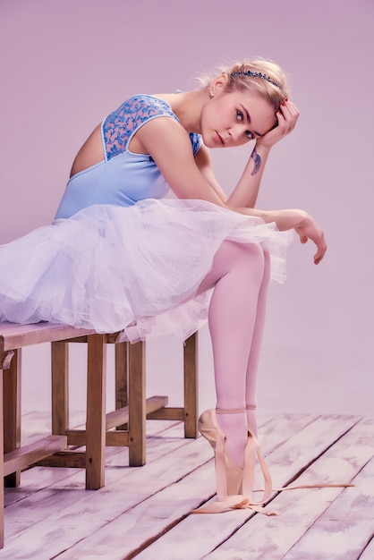 Free photo tired ballet dancer sitting on the wooden floor