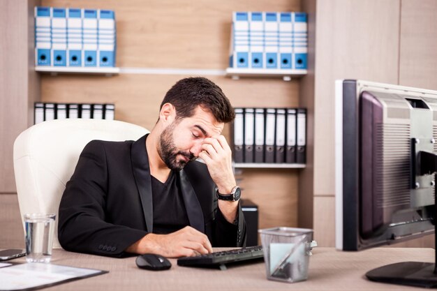 Tired Businessman working in his office. Businessperson in professional environment