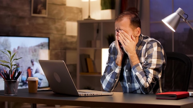 Tired businessman yawn and rubbing eyes in home office during late night hours. Overworked businessman.