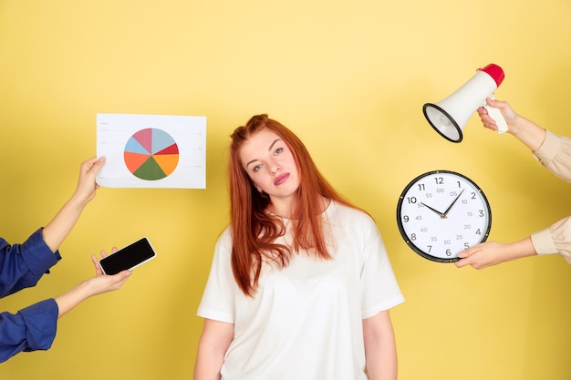 Tired. Caucasian young woman's portrait on yellow studio background, too much tasks. How to manage time right. Concept of office working, business, finance, freelance, self management, planning.