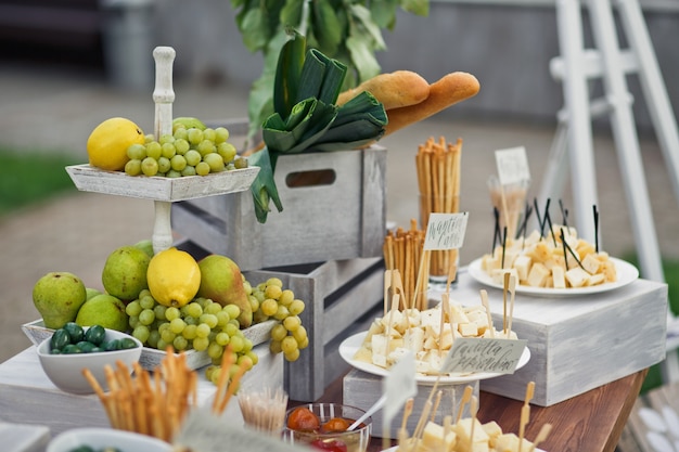 Free photo tired dish with lemons and grape stands on table with cheese