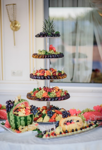 Free photo tired dish with sliced plums, grape, ananas and other fruits