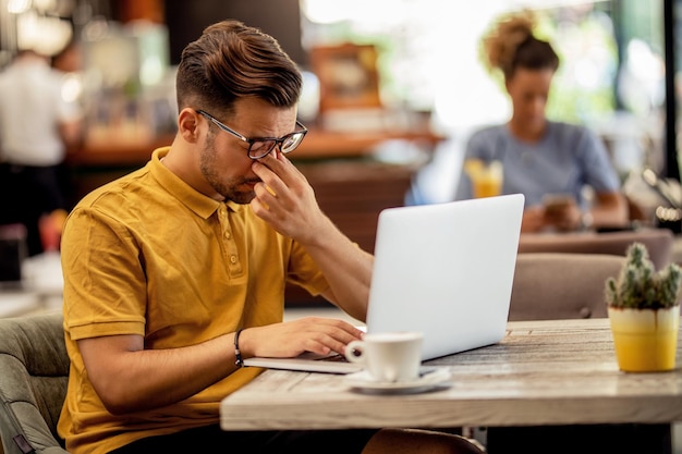 Tired freelancer feeling pain while working on a computer in a bar