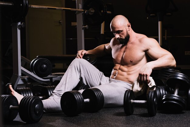 Tired man amidst dumbbells