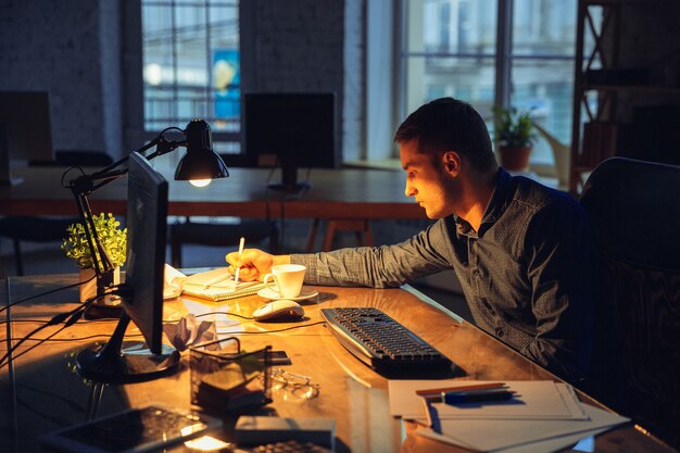 Tired. Man working in office alone, staying to late night.