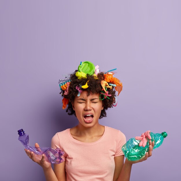 Tired miserable woman holds crumpled plastic bottles