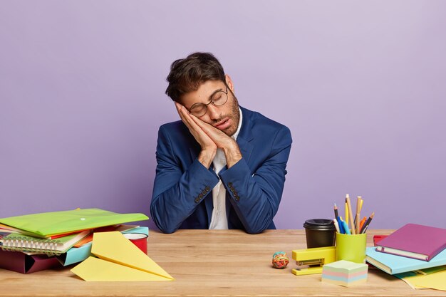 Tired overworked businessman sitting at the office desk