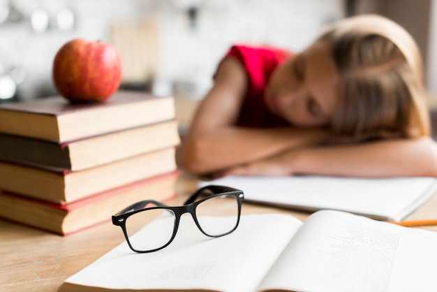 Tired schoolgirl sleeping at desk