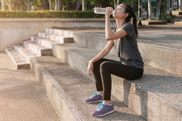 Tired sportswoman drinking water