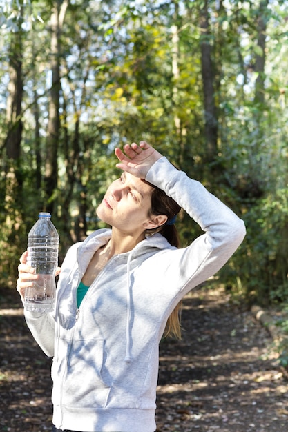 Free photo tired woman drinking water and wiping her sweat