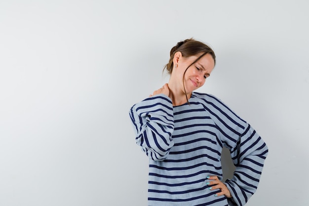 The tired woman is looking down by holding her hand behind nech on white background