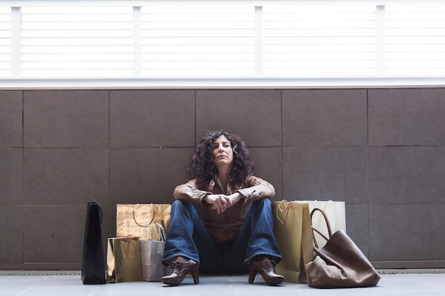 Tired woman sitting with shopping bags on street