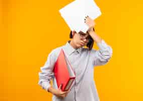 Free photo tired young call center girl wearing glasses holding folder and documents above head looking down isolated on orange wall