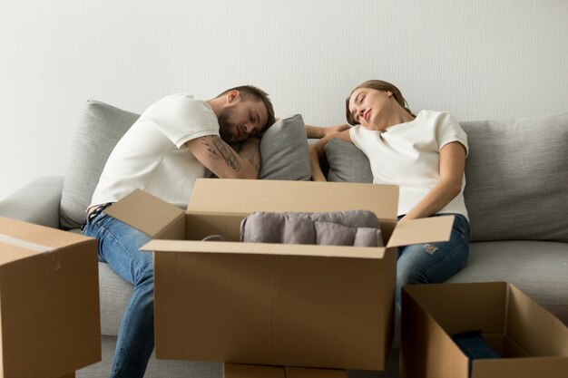 Tired young couple relaxing on sofa moving to new house