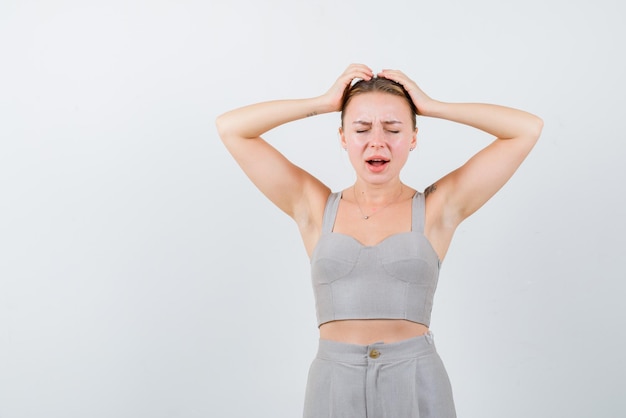 Tired young girl covering her head with hands on white background