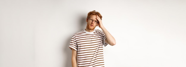 Free Photo tired young man student touching head looking complex and tired standing over white background