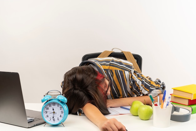 Free photo tired young student girl wearing glasses sleeping at desk with university tools isolated on white background