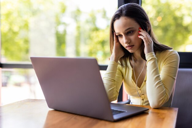 Tired young woman working on laptop on her workspace