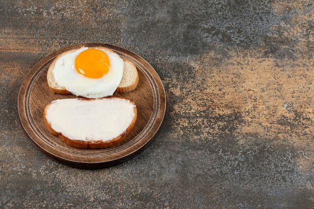 Free photo toast with cream cheese and egg on wooden board.