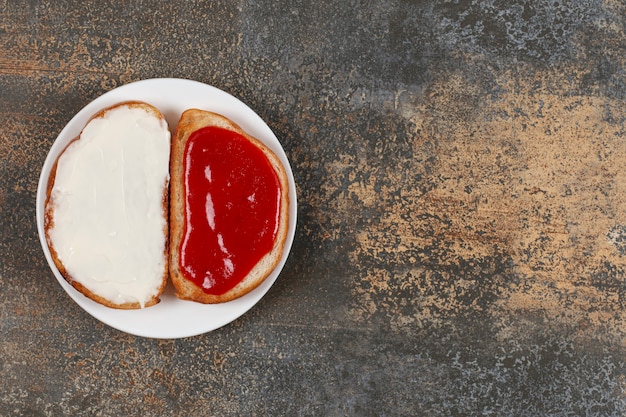 Free photo toasts with strawberry jam and sour cream on white plate.