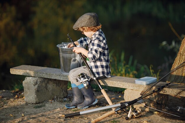 Toddler boy holding a fishing rod Boy wearing plaid shirt Little boy fishing on summer