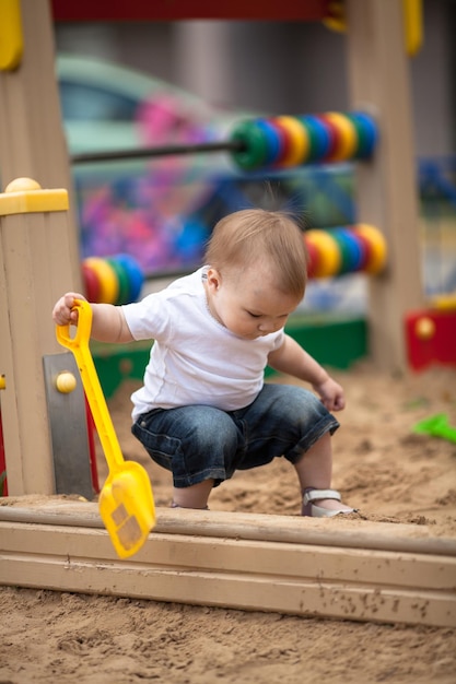 Toddler serious kid playing in sandbox playground