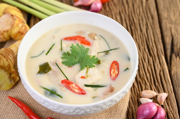 Tom Kha Kai in a bowl with kaffir lime leaves, lemongrass, red onion, galangal and chilli.