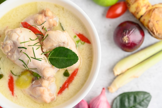 Tom Kha Kai in a bowl with kaffir lime leaves, lemongrass, red onion, galangal and chilli.