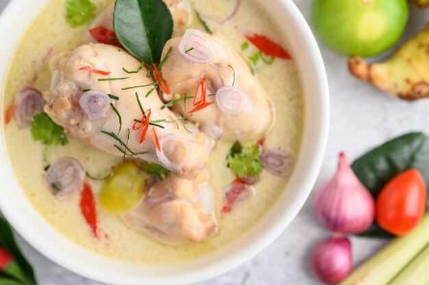 Tom Kha Kai in a bowl with kaffir lime leaves, lemongrass, red onion, galangal and chilli.