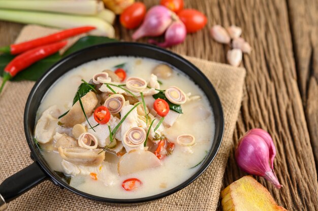 Tom Kha Kai in a pan frying with kaffir lime leaves, lemongrass, red onion, galangal and chilli.