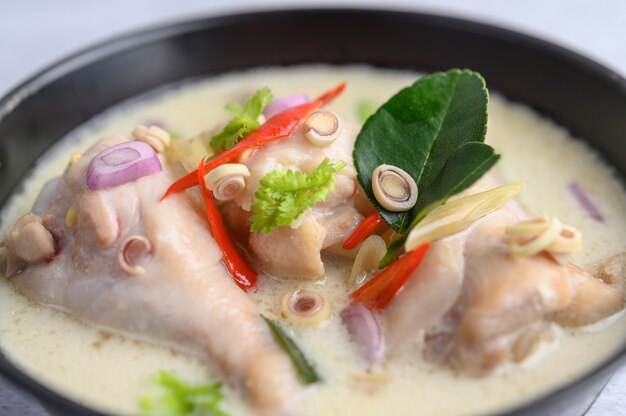 Tom Kha Kai in a pan frying with kaffir lime leaves, lemongrass, red onion, galangal and chilli.